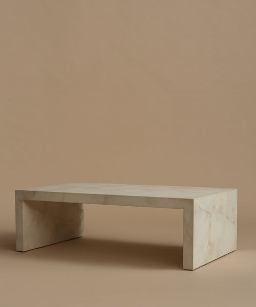 An ivory parchment coffee table with natural detailing against a beige background.