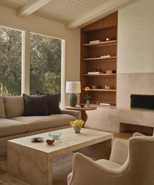 A living room setting with a coffee table, upholstered sofa and boucle accent chairs. 