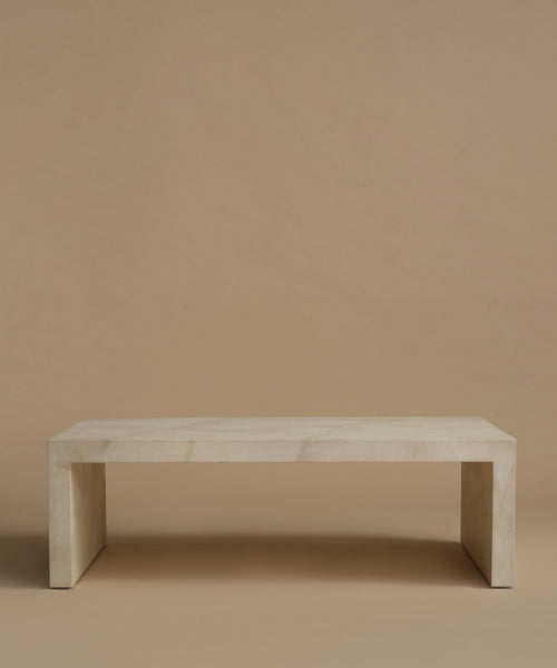 An ivory parchment coffee table with natural detailing against a beige background.