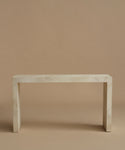 A minimalist console table made of light beige parchment with subtle white veining, set against a solid warm beige background.