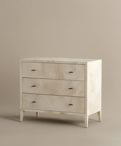 The Napa Dresser features three solid maple drawers, a beige finish, minimalist design, tapered legs, and small black handles, set against a plain light brown background.