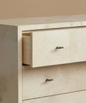 Close-up of a cream-colored marble dresser with two drawers pulled out, featuring dark metal knobs against a neutral beige background.