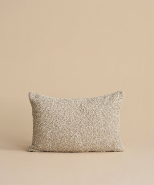 The Nell Boucle Lumbar Pillow, featuring a soft, textured beige fabric, is centered upright against a matching beige background.