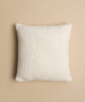 The Nell Boucle Pillow, a square white textured pillow, is displayed from above on a light beige background.