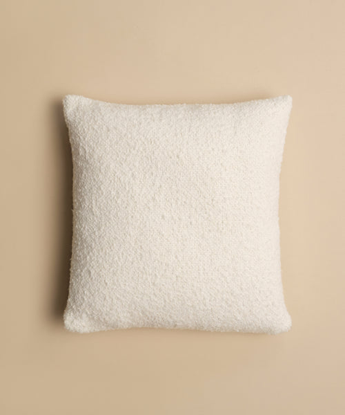 The Nell Boucle Pillow, a square white textured pillow, is displayed from above on a light beige background.