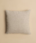 The Nell Boucle Pillow, a square textural cushion in beige, is shown from above on a solid light tan background.