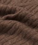 Close-up of the Nell V-Neck Sweater, showcasing its brown cable knit texture, intertwining stitches, and soft, cozy feel that defines this classic style.