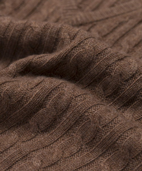 Close-up of the Nell V-Neck Sweater, showcasing its brown cable knit texture, intertwining stitches, and soft, cozy feel that defines this classic style.