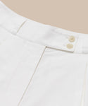 Close-up of the waistband on Newport Short summer shorts in white Italian cotton poplin, with two beige buttons and belt loops, set against a light beige background.