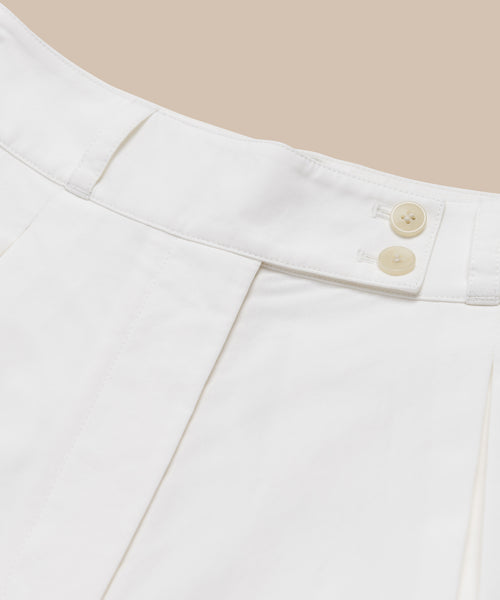 Close-up of the waistband on Newport Short summer shorts in white Italian cotton poplin, with two beige buttons and belt loops, set against a light beige background.