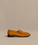 The Nubuck Dylan Loafer, crafted in tan nubuck with decorative stitching, a folded upper detail, and a low black heel, is made in Italy and shown on a plain beige background.
