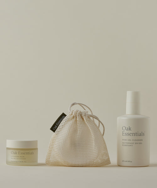 The Double Cleanse Set, featuring a Cleansing Balm and Pure Gel Cleanser in a mesh drawstring bag, is arranged against a neutral background for a hydrated complexion.
