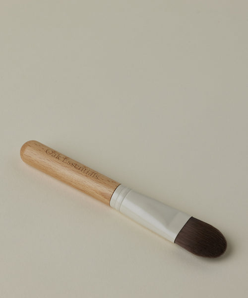 The Mask Brush features a light wooden handle, silver ferrule, and brown bristles engraved with Oak Essentials—perfect for applying your restorative mask during an at-home spa ritual.