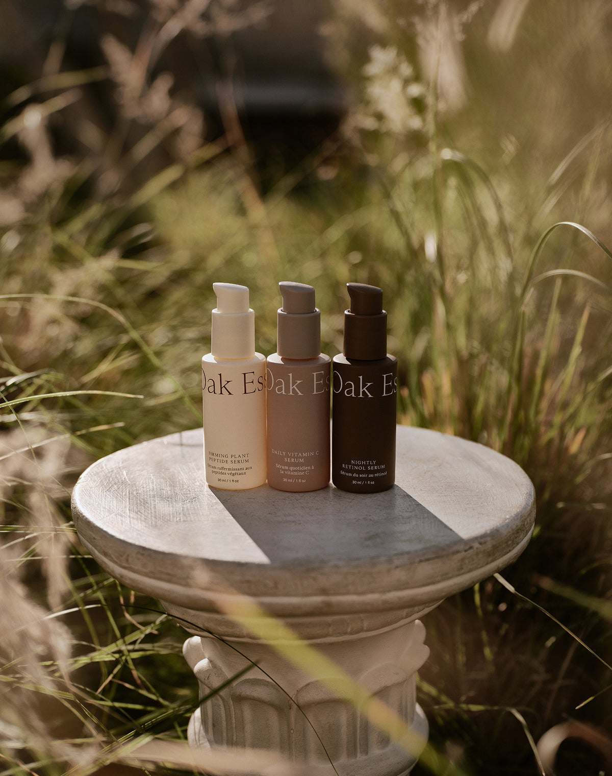 Three bottles of Oak Essentials skincare products on a stone pedestal with a natural background.