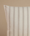 A white and tan stripe pillow against a beige background.
