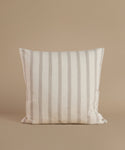 A white and tan stripe pillow against a beige background.