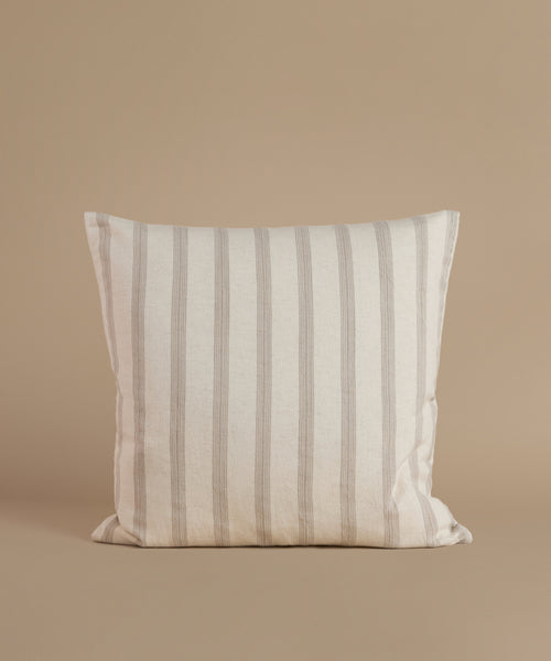 A white and tan stripe pillow against a beige background.