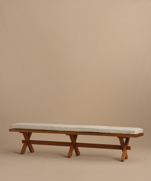 The Outdoor Garden Dining Bench features a long solid teak frame, X-shaped legs, and a Tempotest fabric cushion—ideal for outdoor dining—shown against a plain beige background.