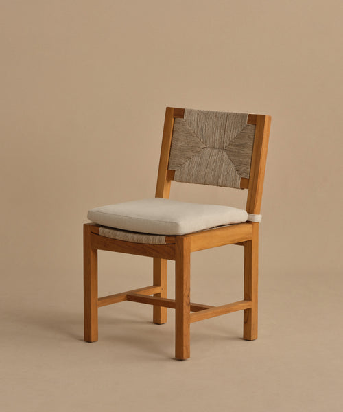 The Outdoor Montecito Dining Chair features a sturdy teak frame, light beige cushion, and woven backrest. Its simple, modern design with clean lines makes it perfect for durable outdoor dining arrangements.