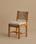 The Outdoor Montecito Dining Chair features a solid teak frame, light beige cushioned seat, and an ECOLENE woven backrest, displayed against a plain beige background.