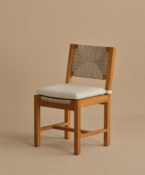 The Outdoor Montecito Dining Chair features a solid teak frame, light beige cushioned seat, and an ECOLENE woven backrest, displayed against a plain beige background.
