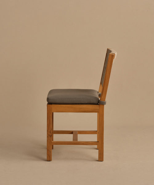 The Outdoor Montecito Dining Chair, made of solid teak with a gray cushioned seat and straight backrest, is shown in profile against a plain beige background.