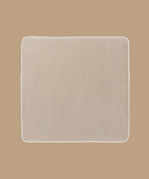 The Outdoor Vista Chair Cushion is a square, beige mat with rounded corners, crafted from premium Italian fabric and shown against a light brown background.