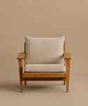 The Outdoor Vista Chair Cushion features a beige upholstered seat and back in Italian fabric, set on a wooden armchair with wide armrests against a plain light brown background.