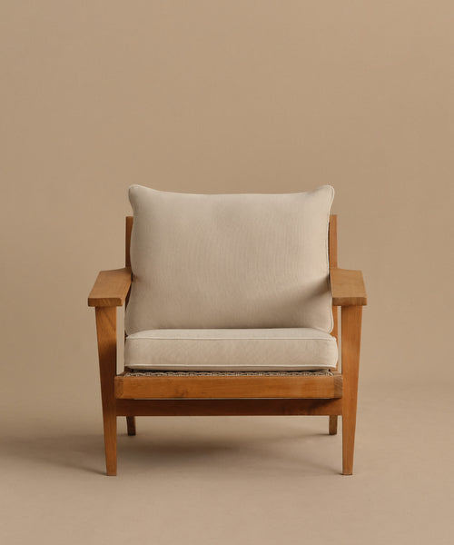 The Outdoor Vista Chair Cushion features a beige upholstered seat and back in Italian fabric, set on a wooden armchair with wide armrests against a plain light brown background.