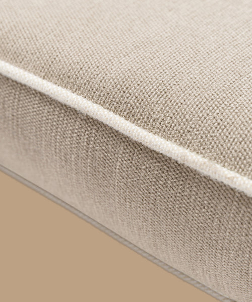 Close-up of the Outdoor Vista Chair Cushion in beige textured Italian fabric, featuring visible edge stitching, set against a plain light brown background.