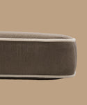 A close-up side view of the Outdoor Vista Chair Cushion, a brown rectangular cushion with white piping made from Italian fabric, set against a plain beige background.