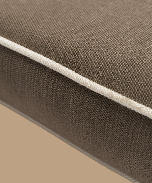 Close-up of the Outdoor Vista Chair Cushion, showcasing brown textured Italian fabric and white piping detail, set against a neutral beige background.