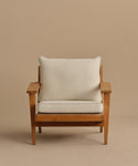 The Outdoor Vista Chair features wide armrests and visible wood grain, with light beige Tempotest fabric cushions. Its simple, modern design is showcased against a plain tan background.