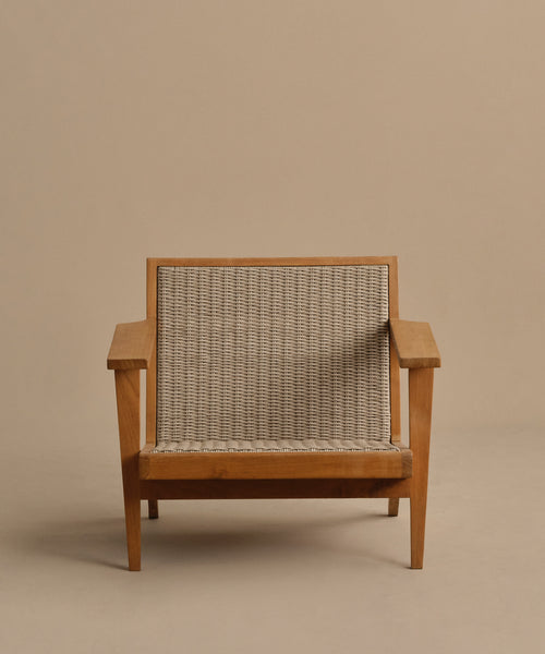 The Outdoor Vista Chair features wide armrests, angled legs, and a woven ECOLENE seat and backrest. Set on a plain beige background, this teak chair offers a sturdy, modern design ideal for stylish outdoor spaces.