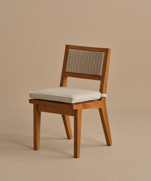 The Outdoor Vista Dining Chair showcases a simple, modern design with a beige cushioned seat and woven ECOLENE rattan backrest, crafted from wood and displayed against a plain tan background.