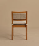 The Outdoor Vista Dining Chair, made of solid teak with a woven ECOLENE rattan backrest and a light cushioned seat, is shown from behind against a plain beige background.
