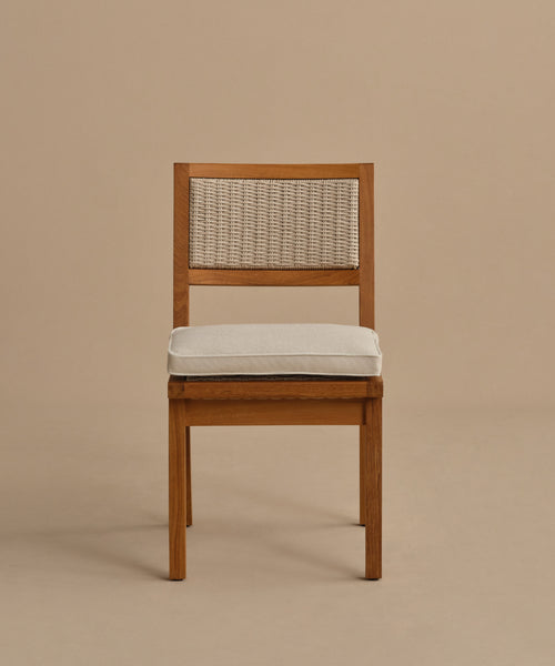 The Outdoor Vista Dining Chair features solid teak construction, a woven ECOLENE backrest, and a light-colored seat cushion, displayed against a plain beige background.