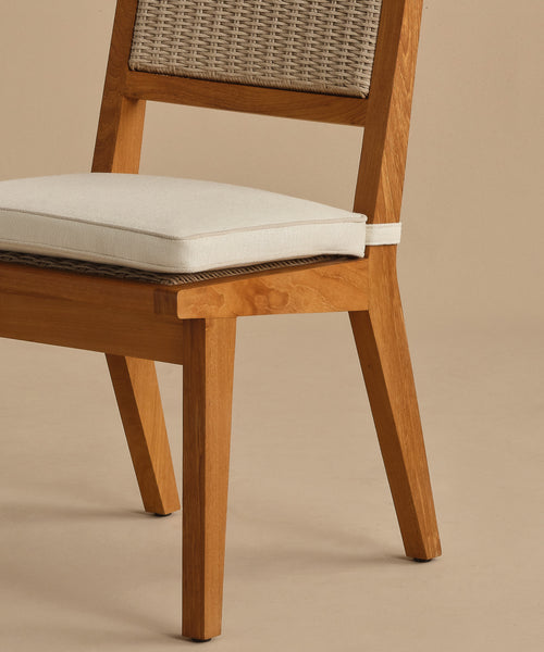 The Outdoor Vista Dining Chair features a solid teak frame, woven ECOLENE backrest, and a light cushioned seat. Shown partially against a beige background, its seat, back, and legs are visible.