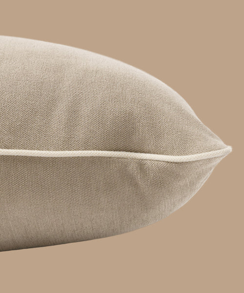 A close-up of the Outdoor Vista Lounge Cushion in beige linen with white piping, set against a matching beige background.