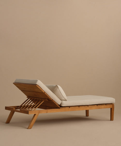 The Outdoor Vista Lounge Chair features a teak frame, light beige cushions, and an adjustable backrest, creating a durable and stylish outdoor seating option shown against a plain beige background.