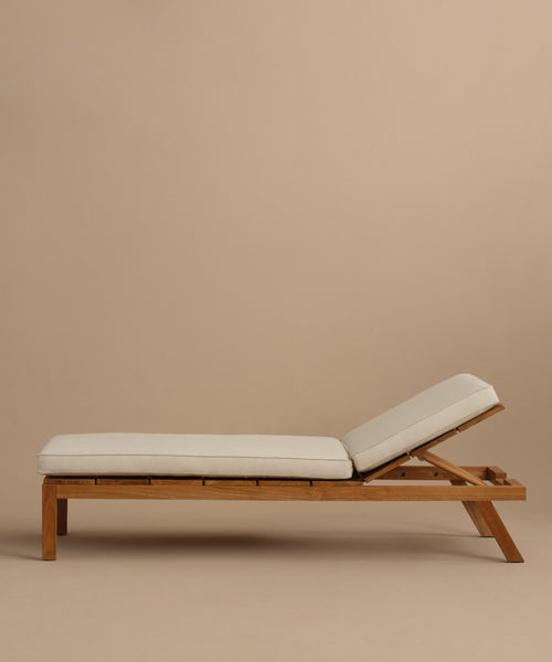 The Outdoor Vista Lounge Chair features light beige cushions and a slightly reclined backrest, shown in profile against a plain beige background, highlighting the chair’s elegant, durable, and comfortable design.