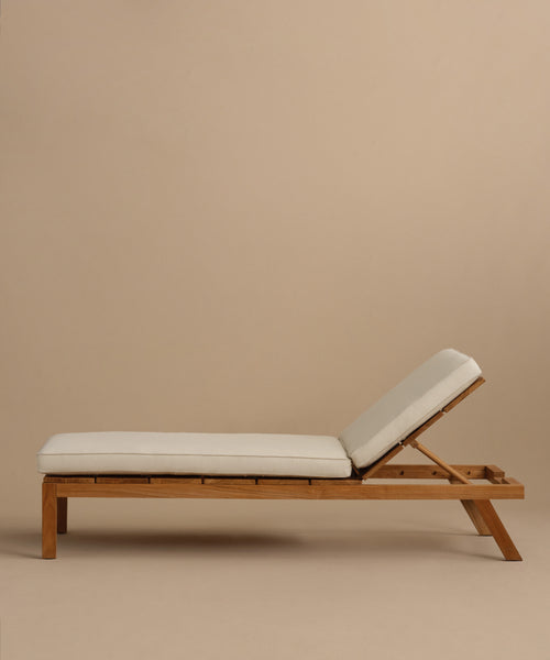 The Outdoor Vista Lounge Chair is a wooden outdoor lounge chair with light beige cushions and an adjustable backrest, designed for durability and shown against a plain beige background.