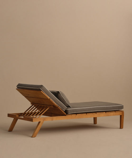 The Outdoor Vista Lounge Chair, shown with dark gray cushions against a beige background, features an adjustable backrest and a modern teak design—ideal for stylish outdoor relaxation.