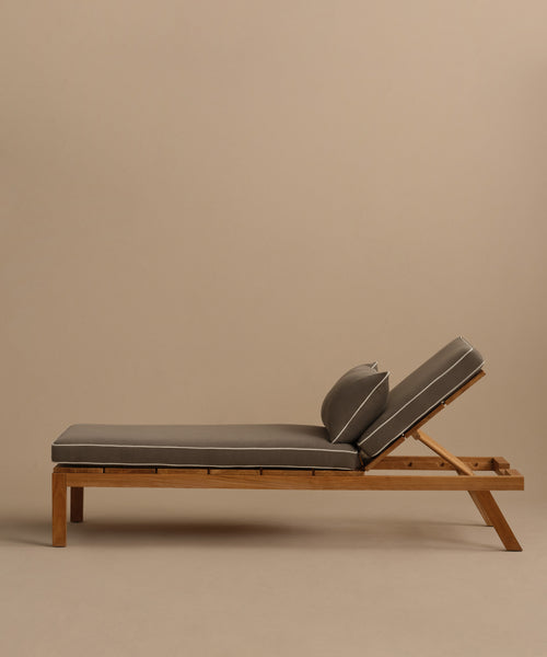 The Outdoor Vista Lounge Chair features a teak frame, gray cushions, and an adjustable backrest. Weather-resistant and stylish, it is showcased against a plain beige background.