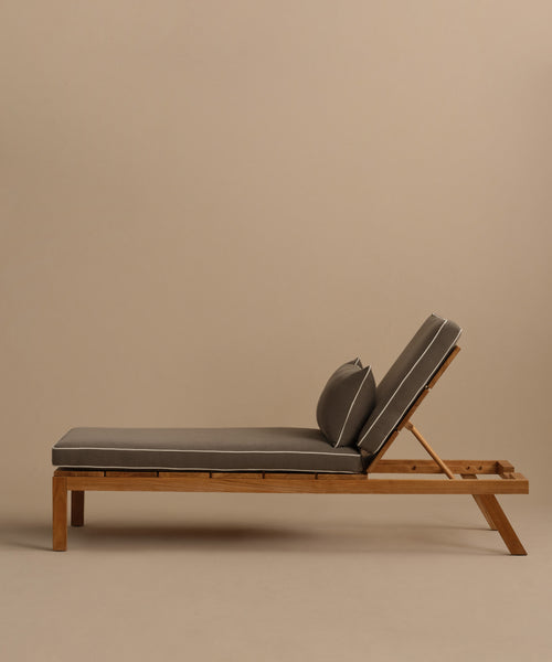 The Outdoor Vista Lounge Chair features a modern teak frame, cushioned seat, adjustable backrest, and matching pillow. Shown on a beige background, this weather-resistant chair adds style and comfort to any patio or outdoor setting.