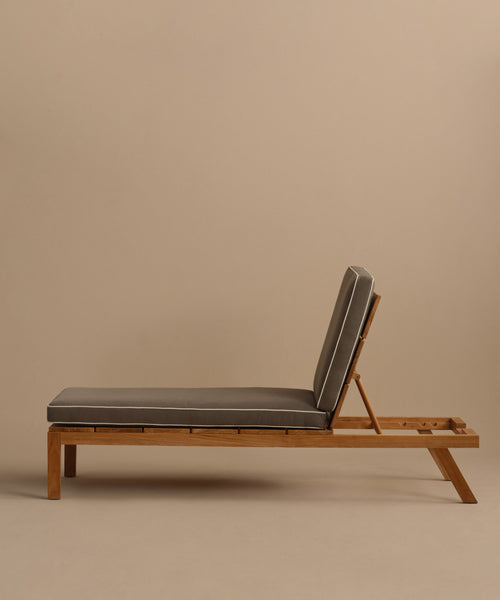 The Outdoor Vista Lounge Chair, featuring a cushioned seat, adjustable backrest, and minimalist teak design, is shown in side profile against a plain beige background—perfect for stylish outdoor lounging.