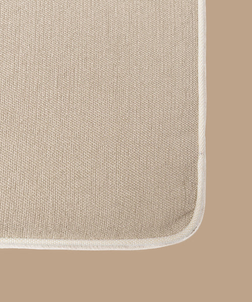 Close-up of the Outdoor Vista Sofa Cushion’s corner, showcasing its piped edge and Italian fabric in beige, set against a matching background. The texture of the Vista Collection material is clearly visible.