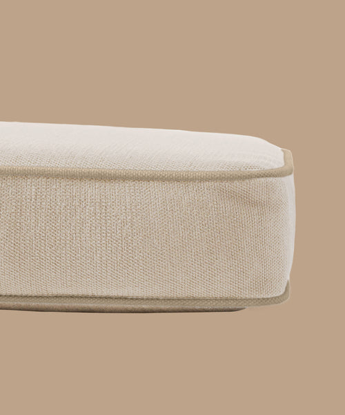 A close-up of the Outdoor Vista Sofa Cushion—a rectangular, fabric-upholstered cushion in light beige Italian fabric with rounded edges and piping—shown on a matching background; ideal for outdoor sofas.