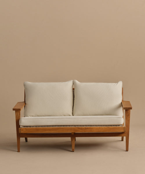 The Outdoor Vista Sofa, with a wooden frame, angled arms and legs, and off-white Tempotest fabric cushions, is displayed against a plain beige background.