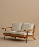 The Outdoor Vista Sofa features a wooden frame, angled legs, light Tempotest fabric cushions, and woven cane accents on the sides, displayed against a plain beige background.